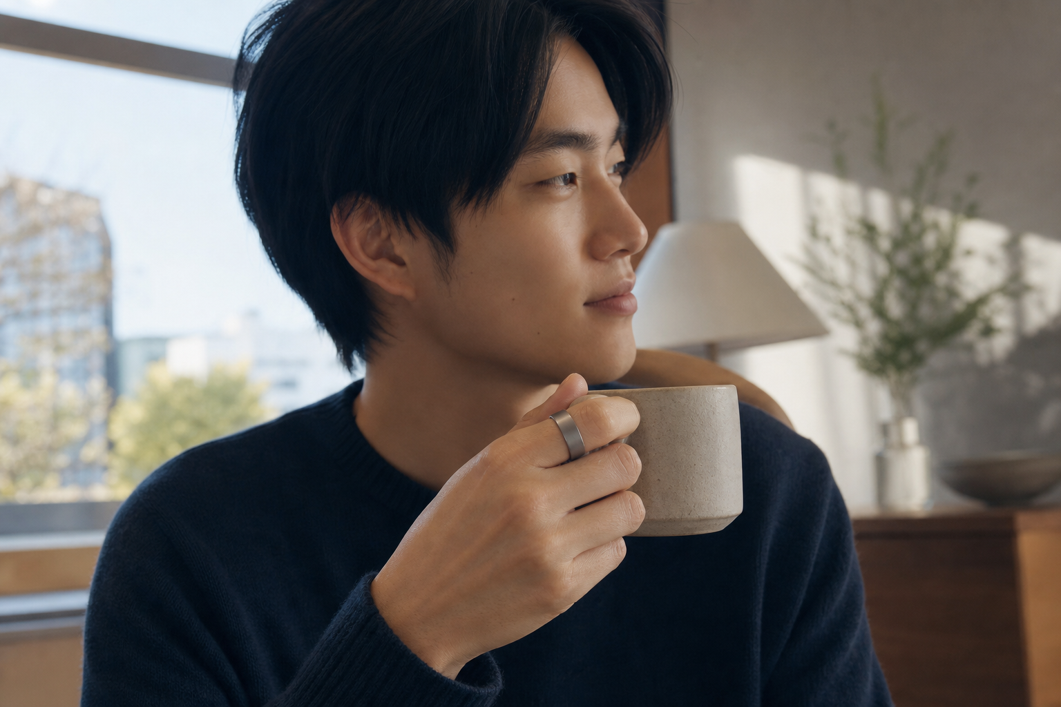 朝のコーヒーを持つ手にスマートリングをつけた様子
