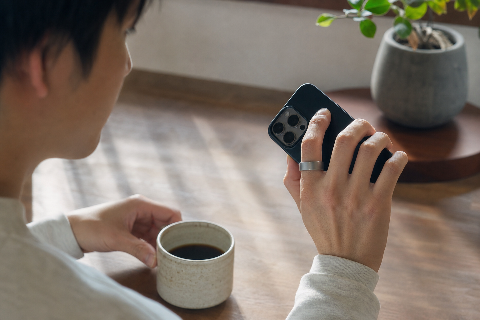 朝のコーヒータイムにスマートフォンで回復スコアを確認する生活シーン