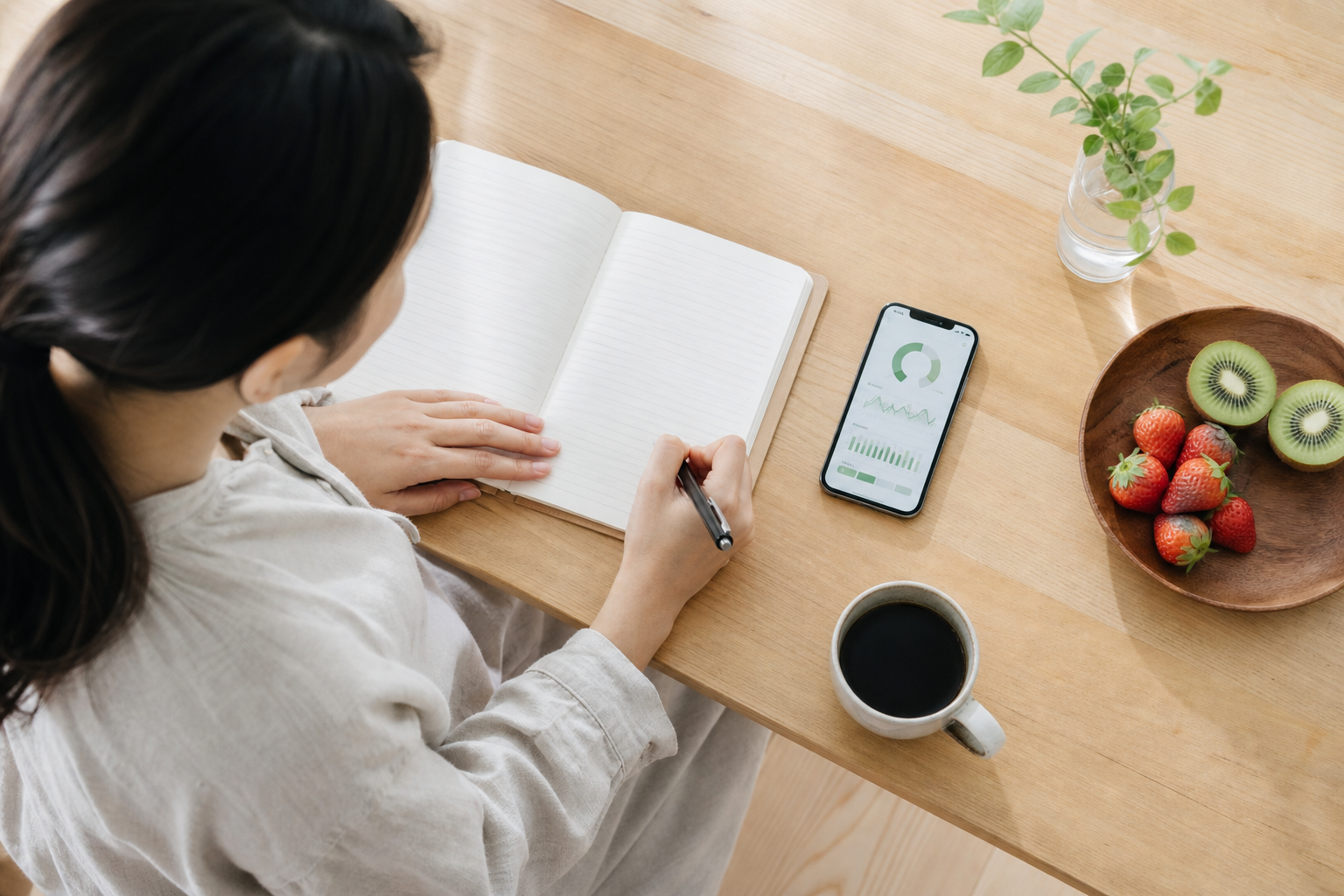 朝にスマホで睡眠データを確認しながらノートを書く人物の生活シーン